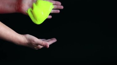 Kız yeşil balçık yoğuruyor. Kadının elleri siyah arka planda parlak yeşil bir balçığı birbirine yaklaştırıyor. Rahatlamak için stres önleyici oyuncak. Eğlenceli bir duyusal aktivite. Oyuncakçı konsepti