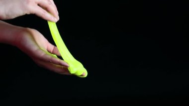 Kız yeşil balçık yoğuruyor. Kadının elleri siyah arka planda parlak yeşil bir balçığı birbirine yaklaştırıyor. Rahatlamak için stres önleyici oyuncak. Eğlenceli bir duyusal aktivite. Oyuncakçı konsepti