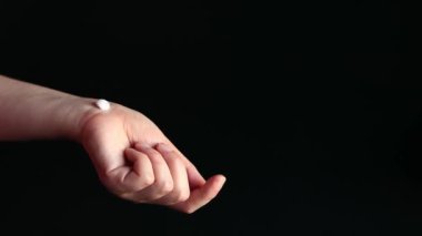 El kremi süren bir kadın, siyah arka plan. Cilde nemlendirici krem. Yaşlanma önleyici kozmetik. Kadınsı el bakımı. Masaj hareketleri kullanarak cildine el kremi süren bir kız.