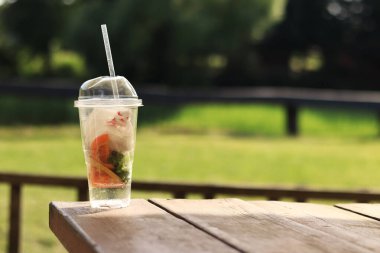 İçinde çöp olan plastik bardaklar, yakın plan. Çöplerin uygunsuz bir şekilde atılması, gezegenin plastik ve diğer çöplerle kirlenmesi. Masada kirli plastik bardak, bulanık doğa arka planı.