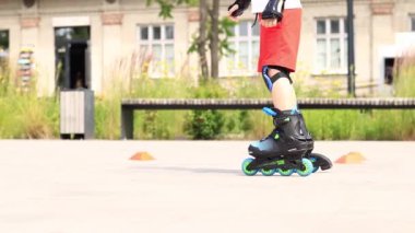 Kyiv, Ukrayna - 23 Haziran 2024: Bir çocuk parkta paten kaymayı öğreniyor, bacakları yakın plan. Bir antrenörle paten yapmayı öğren. Mevsimlik çocuk açık hava sporları. Sağlıklı bir yaşam tarzı. Spor.