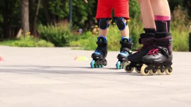 Kyiv, Ukrayna - 23 Haziran 2024: Bir çocuk parkta paten kaymayı öğreniyor, bacakları yakın plan. Bir antrenörle paten yapmayı öğren. Mevsimlik çocuk açık hava sporları. Sağlıklı bir yaşam tarzı. Spor.