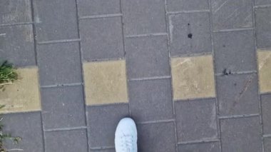 Beyaz spor ayakkabılı kadın bacakları, birinci şahıs görüşü. Yürüyüş ve yürüyüş. Kumaş pantolonlu insan bacakları ve sokakta yürüyen beyaz spor ayakkabılar. Beyaz ayakkabılar. 4K