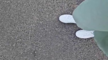 Beyaz spor ayakkabılı kadın bacakları, birinci şahıs görüşü. Yürüyüş ve yürüyüş. Kumaş pantolonlu insan bacakları ve sokakta yürüyen beyaz spor ayakkabılar. Beyaz ayakkabılar. 4K