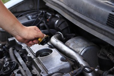 Yağ değişimi. Bir adamın eli yağ dolgu kapağını açar ya da kapatır. Dizel bir arabanın motorunun yağını değiştirmek. Araba bakımı. Eski araba. Tamirci arabayı kontrol ediyor.