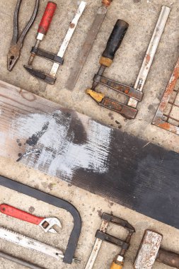 Beton arka planda eski inşaat aletleri, üst manzara. Çekiç, inşaat kıskacı, düz dosya, balyoz, el testeresi ve pense. Antika el aletleri koleksiyonu