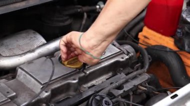 Yağ değişimi. Bir adamın eli yağ dolgu kapağını açar ya da kapatır. Dizel bir arabanın motorunun yağını değiştirmek. Araba bakımı. Eski araba. Tamirci arabayı kontrol ediyor.