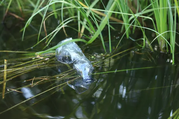 stock image Plastic bottle in water, lake or river. Plastic pollution. Pollution of reservoirs and rivers. Garbage in the river close-up. An abandoned bottle floats on the lake. Food plastic in river water