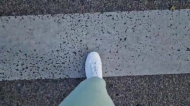 Beyaz spor ayakkabılı kadın bacakları, birinci şahıs görüşü. Yürüyüş ve yürüyüş. Kumaş pantolonlu insan bacakları ve sokakta yürüyen beyaz spor ayakkabılar. Beyaz ayakkabılar. 4K