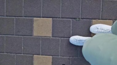 Beyaz spor ayakkabılı kadın bacakları, birinci şahıs görüşü. Yürüyüş ve yürüyüş. Kumaş pantolonlu insan bacakları ve sokakta yürüyen beyaz spor ayakkabılar. Beyaz ayakkabılar. 4K