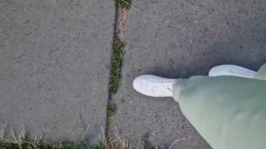 Beyaz spor ayakkabılı kadın bacakları, birinci şahıs görüşü. Yürüyüş ve yürüyüş. Kumaş pantolonlu insan bacakları ve sokakta yürüyen beyaz spor ayakkabılar. Beyaz ayakkabılar. 4K