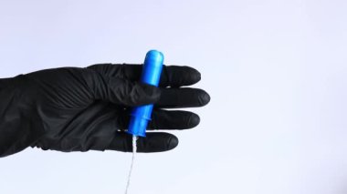 Plastik mavi aplikatörlü bir tampon, kadın hijyeni. Siyah lateks eldivenli eller aplikatörlü tampon tutar. Kadınsı hijyen malzemesi, adet görme. Jinekoloji ve sağlık konsepti