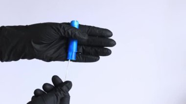 Plastik mavi aplikatörlü bir tampon, kadın hijyeni. Siyah lateks eldivenli eller aplikatörlü tampon tutar. Kadınsı hijyen malzemesi, adet görme. Jinekoloji ve sağlık konsepti
