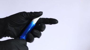 Plastik mavi aplikatörlü bir tampon, kadın hijyeni. Siyah lateks eldivenli eller aplikatörlü tampon tutar. Kadınsı hijyen malzemesi, adet görme. Jinekoloji ve sağlık konsepti