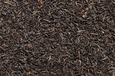 Uzun siyah çay, desenli. Kurutulmuş çay yapraklarının üst görüntüsü. Çay kompozisyonu. Sıcak bir içecek için malzemeler, yakın plan. Arkaplan