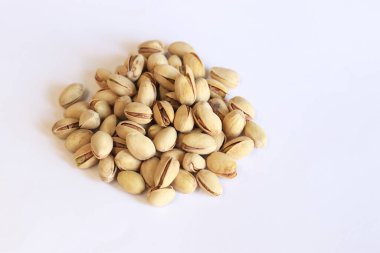 Beyaz arka planda fıstıklar. Hafif arkaplanlı, seçici odaklı bir avuç kuru fıstıklı fıstık. Kabuklu şam fıstığı. Yakın plan.