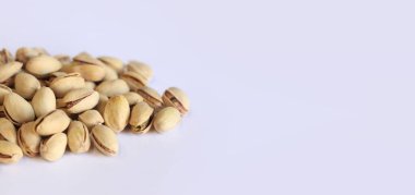 Beyaz arka planda fıstıklar. Hafif arkaplanlı, seçici odaklı bir avuç kuru fıstıklı fıstık. Kabuklu şam fıstığı. Yakın plan.