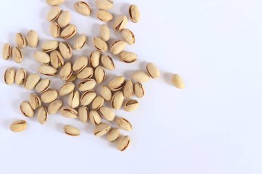 Beyaz arka planda fıstıklar. Hafif arkaplanlı, seçici odaklı bir avuç kuru fıstıklı fıstık. Kabuklu şam fıstığı. Yakın plan.