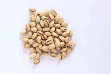 Beyaz arka planda fıstıklar. Hafif arkaplanlı, seçici odaklı bir avuç kuru fıstıklı fıstık. Kabuklu şam fıstığı. Yakın plan.