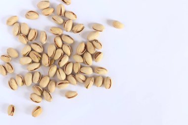 Beyaz arka planda fıstıklar. Hafif arkaplanlı, seçici odaklı bir avuç kuru fıstıklı fıstık. Kabuklu şam fıstığı. Yakın plan.