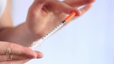 İnsülin şırıngası. Bir kadının eli beyaz arka planda bir şırınga tutuyor, yakın plan. Şeker hastalığı için insülin şırıngası. Diyabet tedavisi. Tıp ve sağlık konsepti