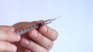 İnsülin şırıngası. Bir kadının eli beyaz arka planda bir şırınga tutuyor, yakın plan. Şeker hastalığı için insülin şırıngası. Diyabet tedavisi. Tıp ve sağlık konsepti