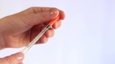 İnsülin şırıngası. Bir kadının eli beyaz arka planda bir şırınga tutuyor, yakın plan. Şeker hastalığı için insülin şırıngası. Diyabet tedavisi. Tıp ve sağlık konsepti