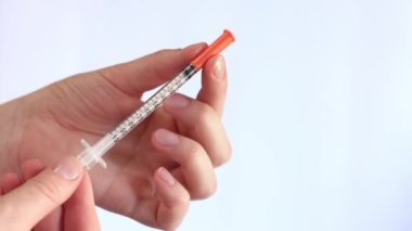 İnsülin şırıngası. Bir kadının eli beyaz arka planda bir şırınga tutuyor, yakın plan. Şeker hastalığı için insülin şırıngası. Diyabet tedavisi. Tıp ve sağlık konsepti