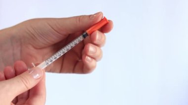 İnsülin şırıngası. Bir kadının eli beyaz arka planda bir şırınga tutuyor, yakın plan. Şeker hastalığı için insülin şırıngası. Diyabet tedavisi. Tıp ve sağlık konsepti