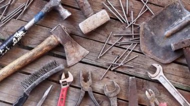 Tahta yüzeyde eski bir alet, üst manzara. Balyoz, kerpeten, balta, kürek, anahtar, düz dosya ve çivi. Paslı eski el aletleri. Çalışma aracı
