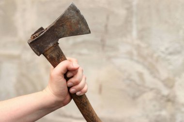 Bulanık duvar arkaplanındaki kadın ellerinde bir balta. Paslı eski bir balta. Tamir ve inşaat için el aletleri. Bir kadının elindeki baltanın yakın çekimi.