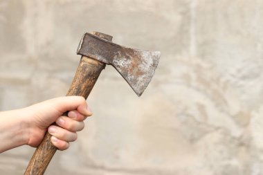 Bulanık duvar arkaplanındaki kadın ellerinde bir balta. Paslı eski bir balta. Tamir ve inşaat için el aletleri. Bir kadının elindeki baltanın yakın çekimi.