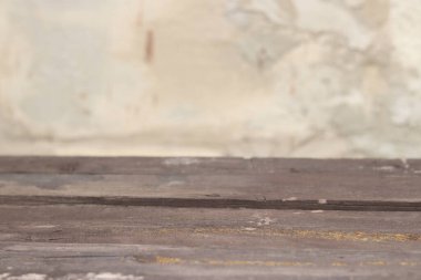 Bulanık beton arka planı olan ahşap tahta masa, seçici odak. Ürün gösterimi veya kurulumu için boş eski tablo ve duvar