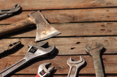 Ahşap bir yüzeyde eski bir el aleti. Ayarlanabilir anahtar, İngiliz anahtarı, balta ve kerpeten. Onarım ve inşaat araçları, seçici odaklanma