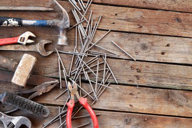 Ahşap bir yüzeyde eski bir el aleti. Ayarlanabilir anahtar, anahtar, balta, çekiç, çivi ve pense. Tamir ve inşaat için aletler, üst manzara. İnşaat geçmişi. Eski paslı bir aletin bileşimi