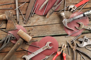 Ahşap bir yüzeyde eski bir el aleti. Ayarlanabilir anahtar, anahtar, balyoz, çekiç, aşındırıcı gıcırdayan tekerlekler ve kerpeten. Tamir ve inşaat için aletler, üst manzara. Eski paslı bir aletin bileşimi