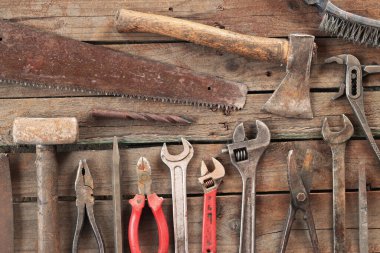 Set of old hand tools for repair, top view. Hand tools on a plank floor. Old hand tools on a wooden surface. Sledgehammer, axe, saw, pliers, adjustable wrench, file and nails. Everything for repair clipart