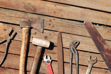 Set of old hand tools for repair, top view. Hand tools on a plank floor. Old hand tools on a wooden surface. Sledgehammer, axe, saw, pliers, wrench and file. Everything for repair clipart