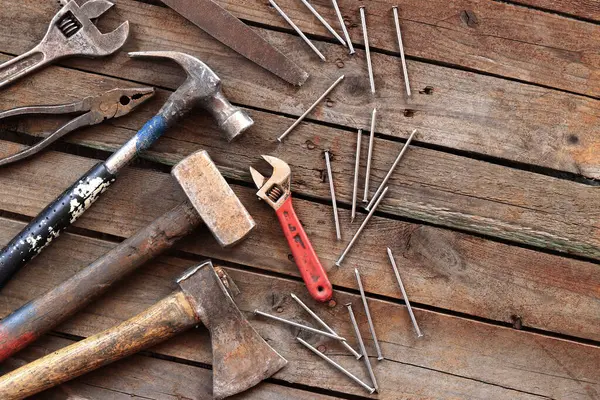 Tamir için eski el aletleri seti, üst manzara. Tahta zeminde el aletleri. Ahşap bir yüzeyde eski el aletleri. Balyoz, balta, testere, kerpeten, ayarlanabilir anahtar, dosya ve çivi. Tamir için herşey