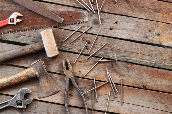 Tamir için eski el aletleri seti, üst manzara. Tahta zeminde el aletleri. Ahşap bir yüzeyde eski el aletleri. Balyoz, balta, testere, kerpeten, ayarlanabilir anahtar, dosya ve çivi. Tamir için herşey