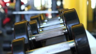 Kadın eli, vücut geliştirme. Salonda dambıllar var. Spor salonunda antreman yapmak için kadın elinin raftan dambılları çekişi. Fitness ekipmanlarıyla güçlü çalışma. Spor konsepti