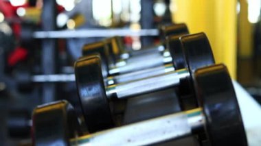 Kadın eli, vücut geliştirme. Salonda dambıllar var. Spor salonunda antreman yapmak için kadın eliyle dambılı askıya yerleştirirken yakın plan. Fitness ekipmanlarıyla güçlü çalışma. Spor konsepti