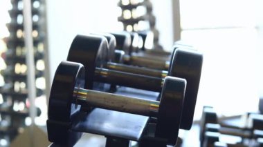 Kadın eli, vücut geliştirme. Salonda dambıllar var. Spor salonunda antreman yapmak için kadın elinin raftan dambılları çekişi. Fitness ekipmanlarıyla güçlü çalışma. Spor konsepti