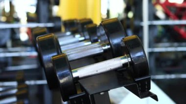 Kadın eli, vücut geliştirme. Salonda dambıllar var. Spor salonunda antreman yapmak için kadın elinin raftan dambılları çekişi. Fitness ekipmanlarıyla güçlü çalışma. Spor konsepti