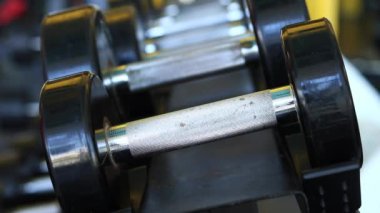 Kadın eli, vücut geliştirme. Salonda dambıllar var. Spor salonunda antreman yapmak için kadın elinin raftan dambılları çekişi. Fitness ekipmanlarıyla güçlü çalışma. Spor konsepti
