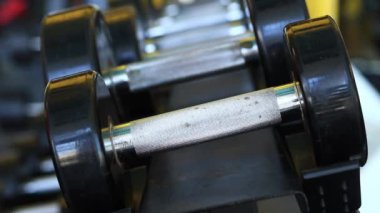 Kadın eli, vücut geliştirme. Salonda dambıllar var. Spor salonunda antreman yapmak için kadın elinin raftan dambılları çekişi. Fitness ekipmanlarıyla güçlü çalışma. Spor konsepti