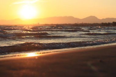 Denizde gün batımı. Balear Denizi, Salou, İspanya. Kumsal, deniz, küçük dalgalar. Sahilde akşam manzarası. Denizde tatil.