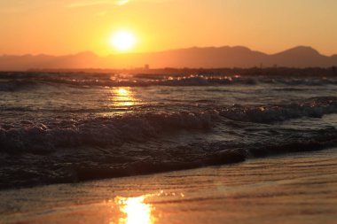 Denizde gün batımı. Balear Denizi, Salou, İspanya. Kumsal, deniz, küçük dalgalar. Sahilde akşam manzarası. Denizde tatil.