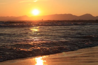 Denizde gün batımı. Balear Denizi, Salou, İspanya. Kumsal, deniz, küçük dalgalar. Sahilde akşam manzarası. Denizde tatil.