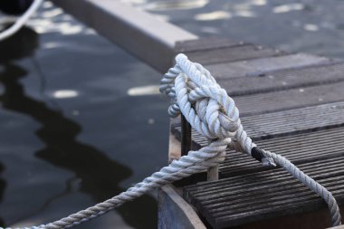 Demirleme kalesi, bir yat iskelesinde bağlama düğümü. Yatın bağlama ipleri diz kapağına bağlı. Halatları bağlamak için iskelede diz çökün. Bağlama ve bağlama ipleri için diz çökün